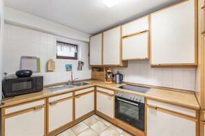 Eine kleine Küche mit Mikrowelle, Spüle und Backofen.