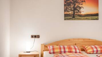 Ein Schlafzimmer mit einem hölzernen Kopfteil, einem Nachttisch mit Lampe und einem Baumgemälde an der Wand.