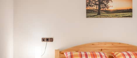 Ein Schlafzimmer mit einem hölzernen Kopfteil, einem Nachttisch mit Lampe und einem Baumgemälde an der Wand.