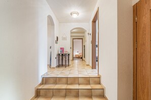 Un couloir avec un escalier menant à une chambre.