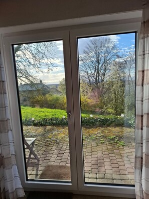 A room with a sliding glass door leading to an outdoor area with a brick pathway and greenery.