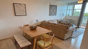 Un comedor con mesa y sillas de madera, un banco, un sofá y dos elementos decorativos en la pared.