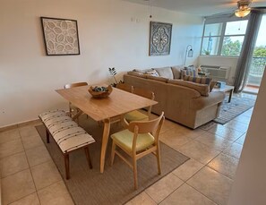 A dining area with a wooden table and chairs, a bench, a sofa, and two wall-mounted decorative pieces. - Sea Beach PH, terrace, stunning views, Beach 2 min (Aguada)