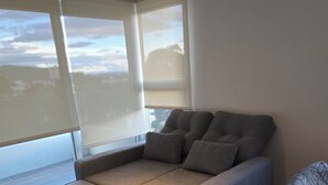 Una habitación moderna con sofá cama, ventanas amplias y vista a la ciudad.