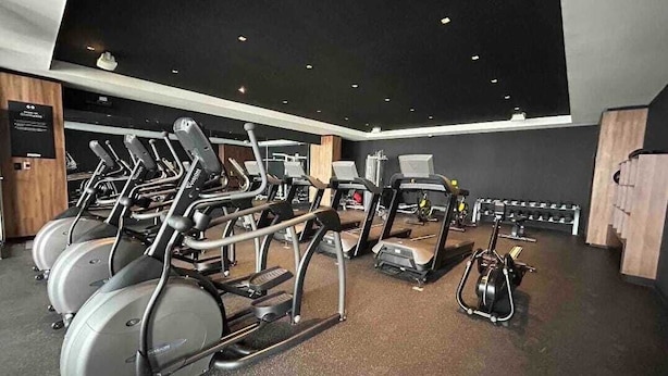 Un gimnasio con cintas de correr, elípticas y bicicletas estáticas.