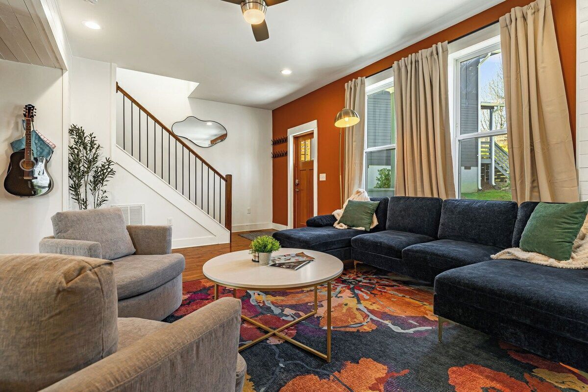 A living room with a staircase, a guitar, a sofa, and a coffee table.