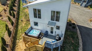Uma casa de dois andares com hidromassagem no pátio, um deck e uma garagem.