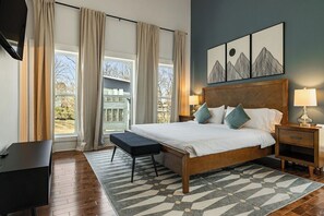Ein Schlafzimmer mit einem großen Bett, Nachttischen, einer Bank und Blick ins Freie.