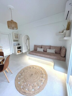Un salon moderne avec un canapé, un tapis rond en fibres naturelles et un coin repas avec des chaises.