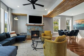 Ein modernes Wohnzimmer mit Kamin, Sofa, Sessel und Essbereich.