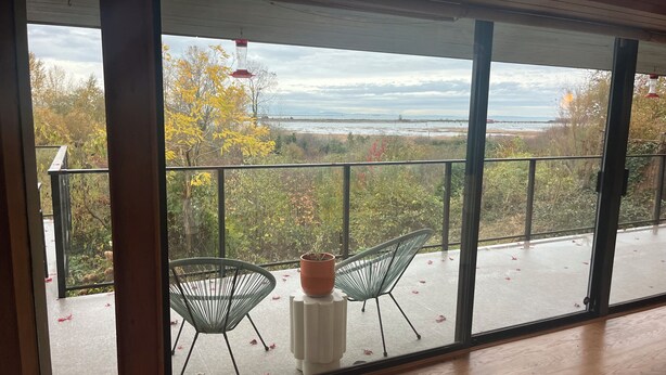 Ein Balkon mit Blick auf das Meer, zwei Stühle und ein Blumentopf.