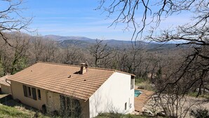 Une maison avec un toit en tuiles, une piscine et une vue sur les montagnes.