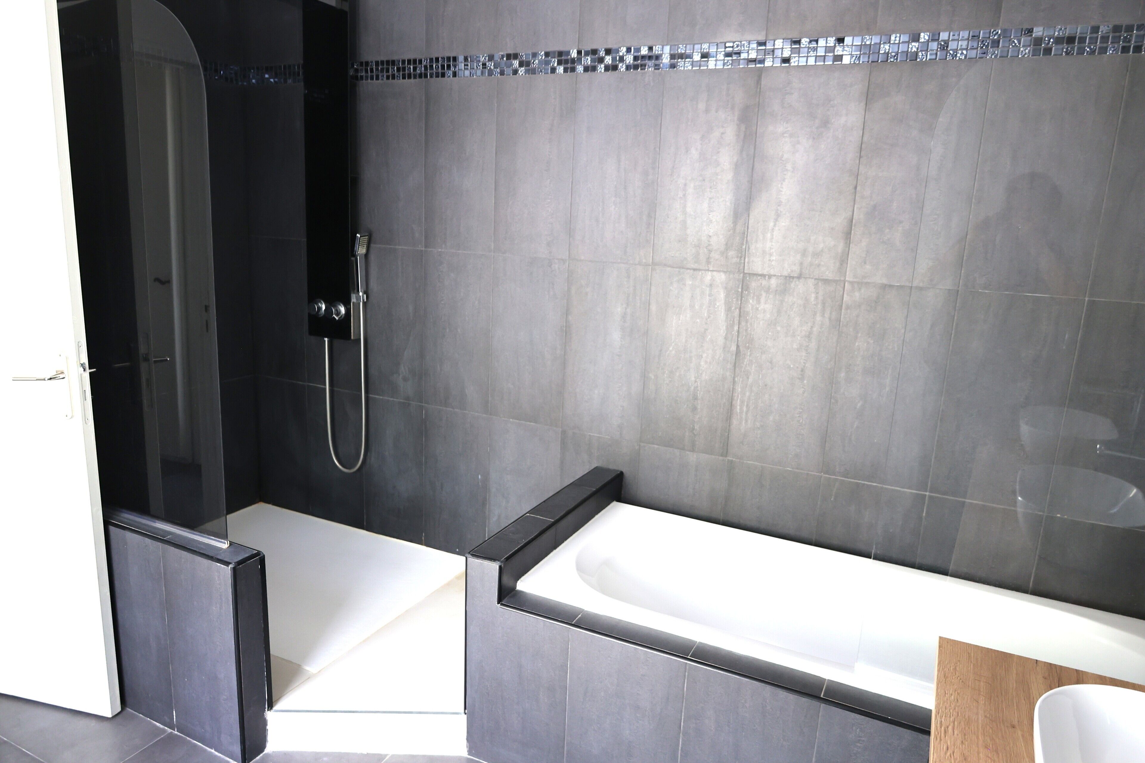 A modern bathroom with a glass-enclosed shower, a standalone bathtub, and a tiled shower area.