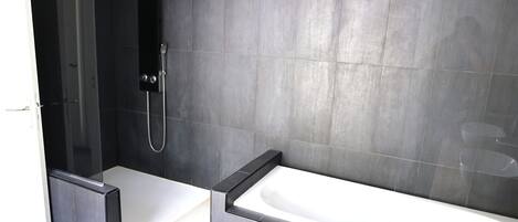 A modern bathroom with a glass-enclosed shower, a standalone bathtub, and a tiled shower area.