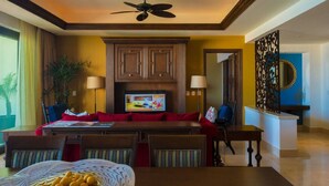 A hotel dining area with a television, wooden cabinets, a dining table with chairs, and a decorative wall piece. - Spacious 2 BR, 3 bath Presidential Suite. Pacific Ocean View. 6 guests welcome! (Cabo San Lucas)