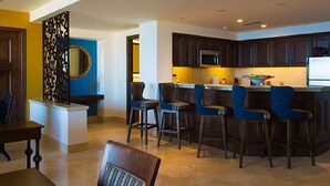 A modern kitchen with dark wooden cabinets, a central island with bar stools, and a microwave. - Spacious 2 BR, 3 bath Presidential Suite. Pacific Ocean View. 6 guests welcome! (Cabo San Lucas)