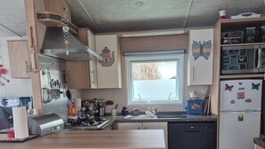 Una cocina compacta con una isla central, taburetes de bar, una ventana y un refrigerador.