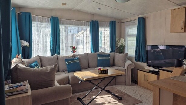 Un espacio habitable compacto con sofá, una mesita, televisión y una zona de kitchenette.