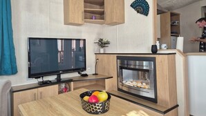 Una cocina moderna con televisor de pantalla plana, horno empotrado y frutero sobre la encimera.