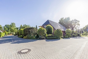 A residential area with a paved driveway, a house with a sloped roof, and well-maintained landscaping.