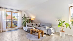 Un salon moderne avec un canapé, une table basse en bois et une plante en pot.
