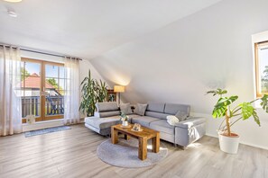 En moderne stue med en sofa, et træsofabord og en potteplante.