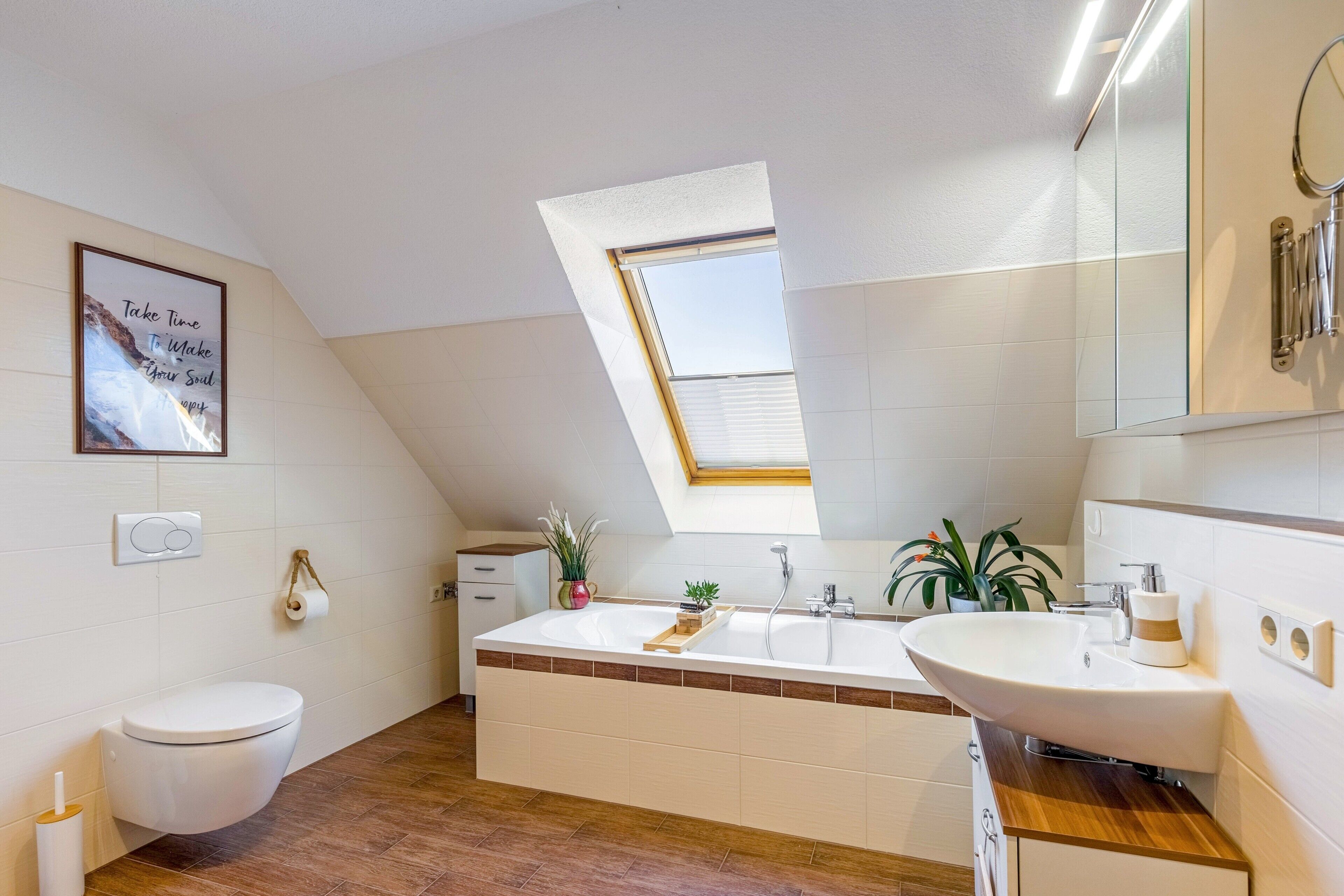 A modern bathroom with a skylight, a large bathtub, and a sink.