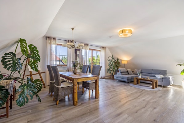 A spacious loft with a dining area, a sofa, and large windows.