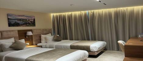 Habitación de hotel con dos camas, un escritorio, una lámpara y un cuadro en la pared.