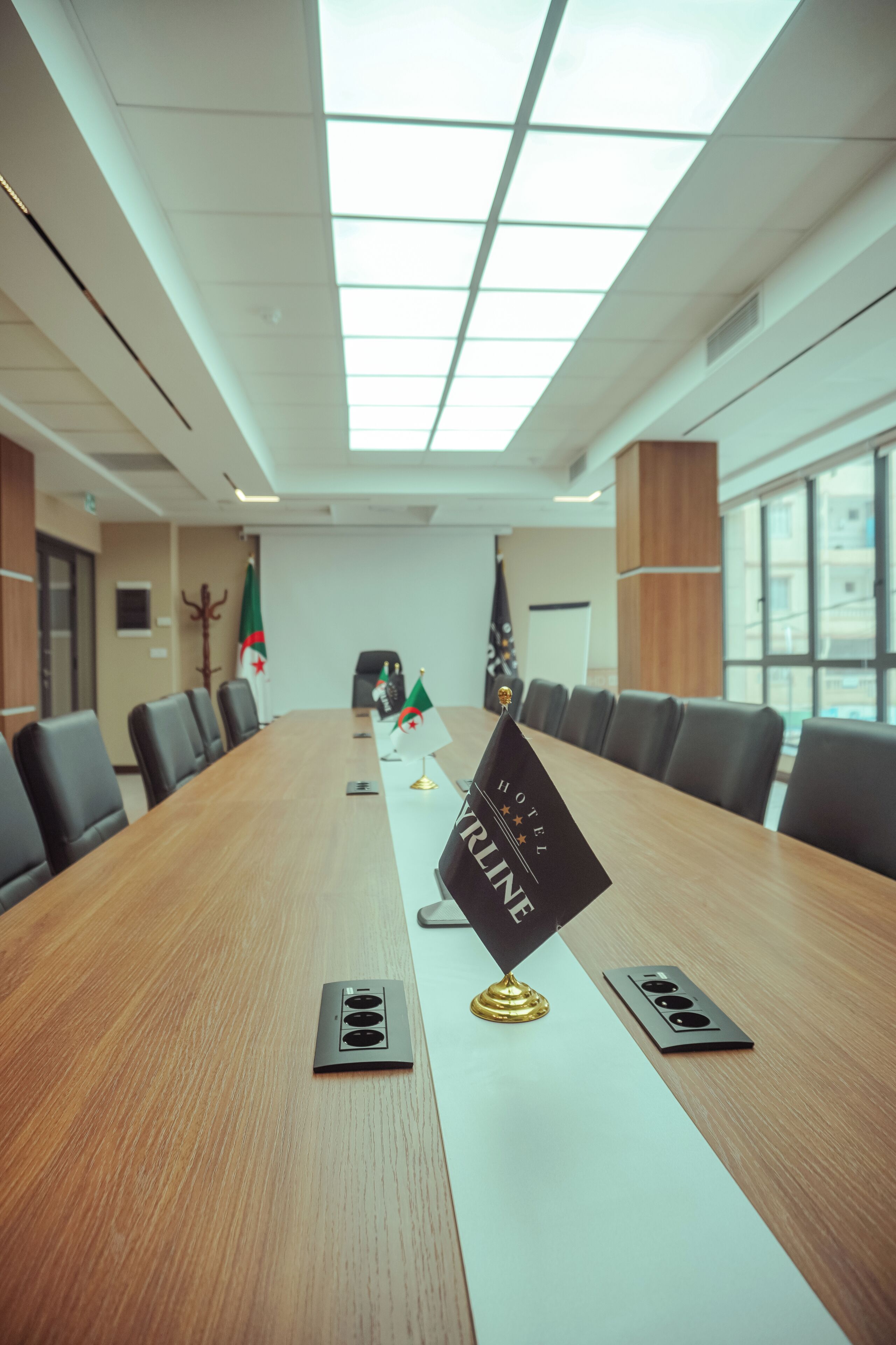 A conference room with a long table, flags, and a 'HOTEL KRINGE' sign.