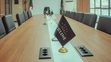 A conference room with a long table, flags, and a 'HOTEL KRINGE' sign.