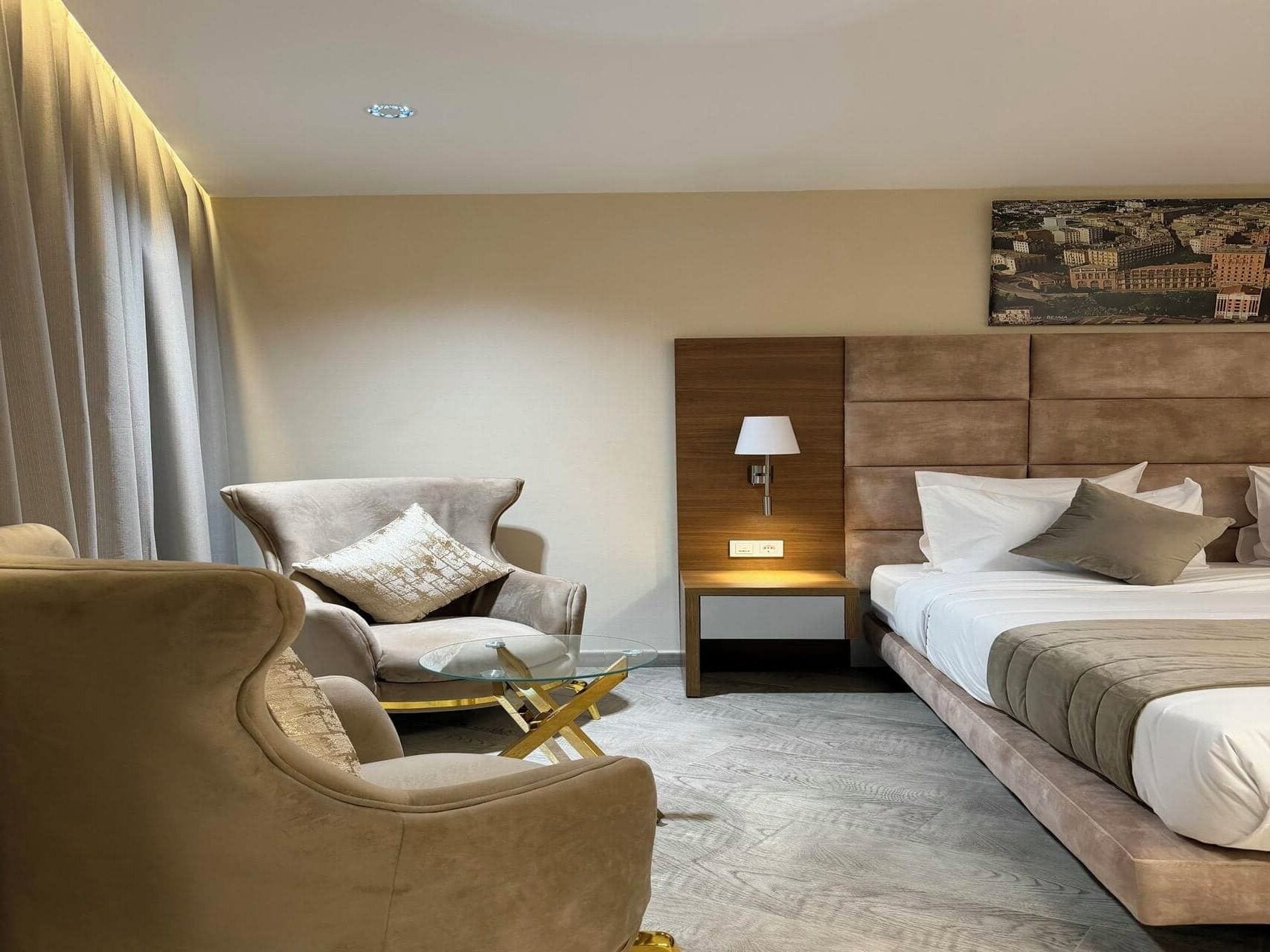 Een hotelkamer met een bed, een stoel, een klein tafeltje, een nachtkastje en een lamp.