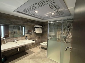 Un baño moderno con cabina de ducha de vidrio, un espejo grande y un tocador con lavabo y perchero para toallas.