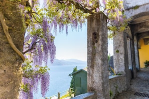 A stone structure with a view of the sea and a small building in the background. - Antica Villa Branca by Lago Maggiore Rentals (Nizzolino, VB)