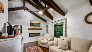 A cozy living room with a fireplace, a sofa, a chair, and a coffee table. - Rustic 2BR Farm Cabin: Hot Tub, Animals & Hiking (Sevierville)
