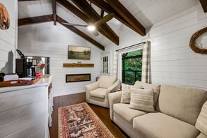 A cozy living room with a fireplace, a sofa, a chair, and a coffee table. - Rustic 2BR Farm Cabin: Hot Tub, Animals & Hiking (Sevierville)