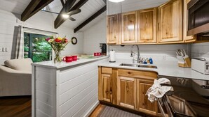 A modern kitchen with wooden cabinets, a white countertop, and a built-in oven. - Rustic 2BR Farm Cabin: Hot Tub, Animals & Hiking (Sevierville)
