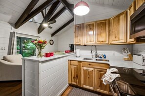 A modern kitchen with wooden cabinets, a white countertop, and a built-in oven. - Rustic 2BR Farm Cabin: Hot Tub, Animals & Hiking (Sevierville)