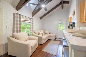 A cozy living room with a sofa and armchair, a wooden ceiling, and a view through a window. - Rustic 2BR Farm Cabin: Hot Tub, Animals & Hiking (Sevierville)