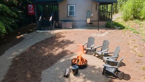 A cabin with a fire pit and Adirondack chairs in the yard. - Rustic 2BR Farm Cabin: Hot Tub, Animals & Hiking (Sevierville)