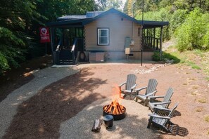 A cabin with a fire pit and Adirondack chairs in the yard. - Rustic 2BR Farm Cabin: Hot Tub, Animals & Hiking (Sevierville)