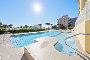 Una piscina con un cielo soleado, vistas despejadas de los edificios circundantes y una zona junto a la piscina bien cuidada.