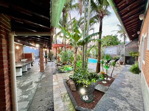 An outdoor patio area with a pool, palm trees, and a brick wall.