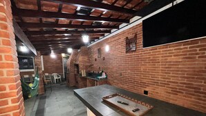 An indoor space with brick walls, a long counter, and a seating area with chairs. - House with pool in Praia Grande with 2 Wi-Fi networks in the house, comfortably accommodates up to 20 people!! (Praia Grande)