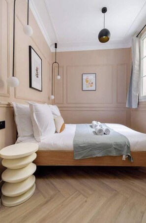 Ein Schlafzimmer mit Bett, Nachttischen, einer Hängeleuchte und einem Fenster mit Vorhängen.