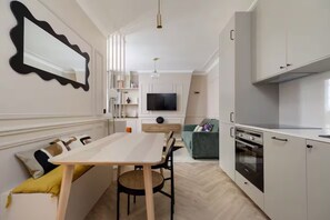 A modern kitchen with a dining area, a TV mounted on the wall, and a built-in oven. - Splendid apartment 1BDR/4PAX in the city center (Paris)