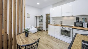 Une cuisine compacte avec des meubles blancs, un plan de travail en bois, un four encastré et un four à micro-ondes.