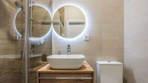 Une salle de bain moderne avec une douche à parois de verre, un lavabo blanc et des toilettes.