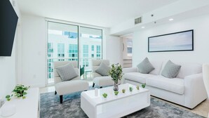 Ein stilvolles Wohnzimmer mit einem weißen Sofa, einem Couchtisch und einem großen Fenster.