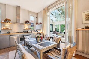 Une cuisine moderne avec un coin repas, de grandes fenêtres et une vue sur la verdure.